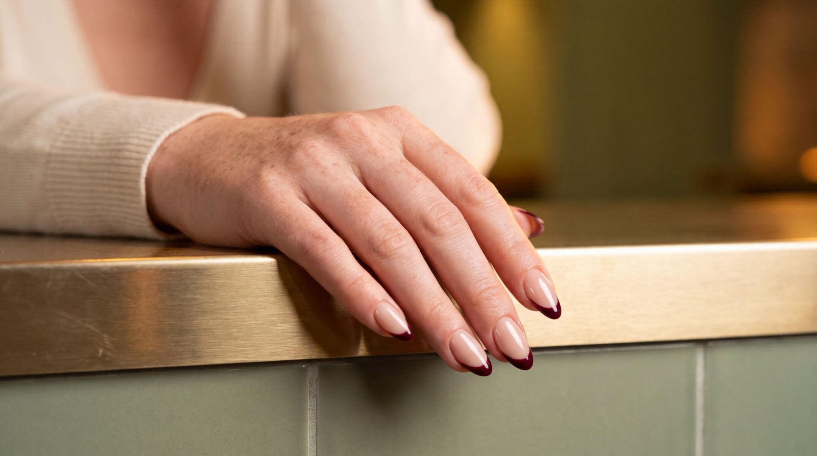 Almond-shaped nails with a glossy nude gel manicure resting on a salon counter