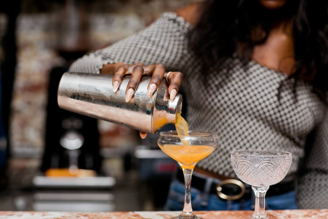 Woman pouring cocktail at the best nail salon in London